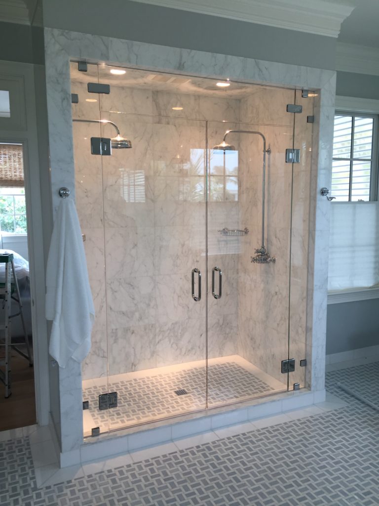 Marble tile shower with double glass doors.